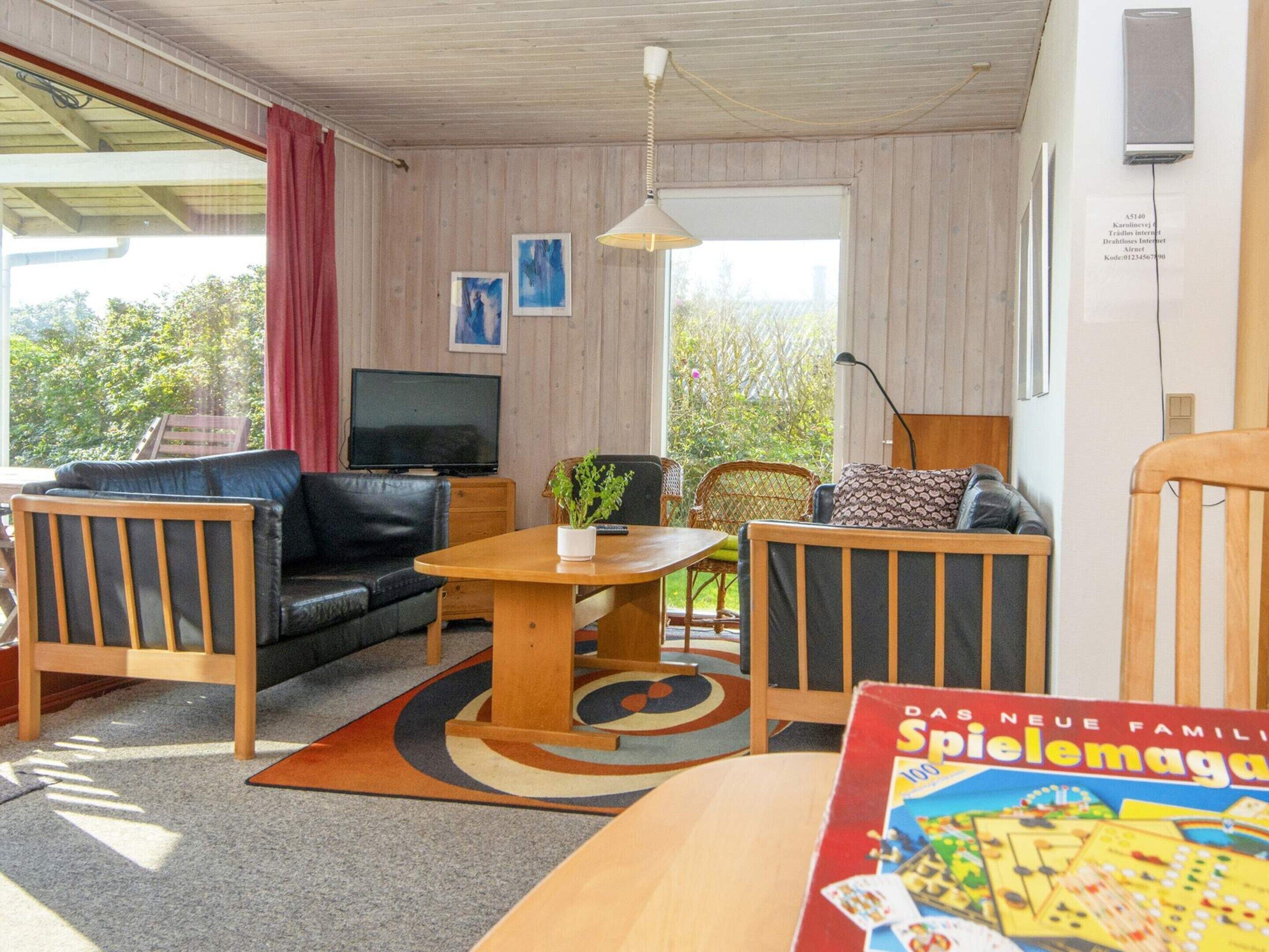 A cozy room with a sofa, chairs, a TV, and a table with a board game.