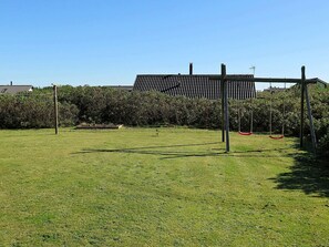 A grassy outdoor area with a metal structure, possibly a pergola, and a swing set. - 8 Person Holiday Home in Harboore (Harboore)