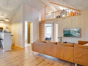Ein modernes Interieur mit einer Holzwand, einer Ledersofa, einer Treppe und einem an der Wand montierten Fernseher.