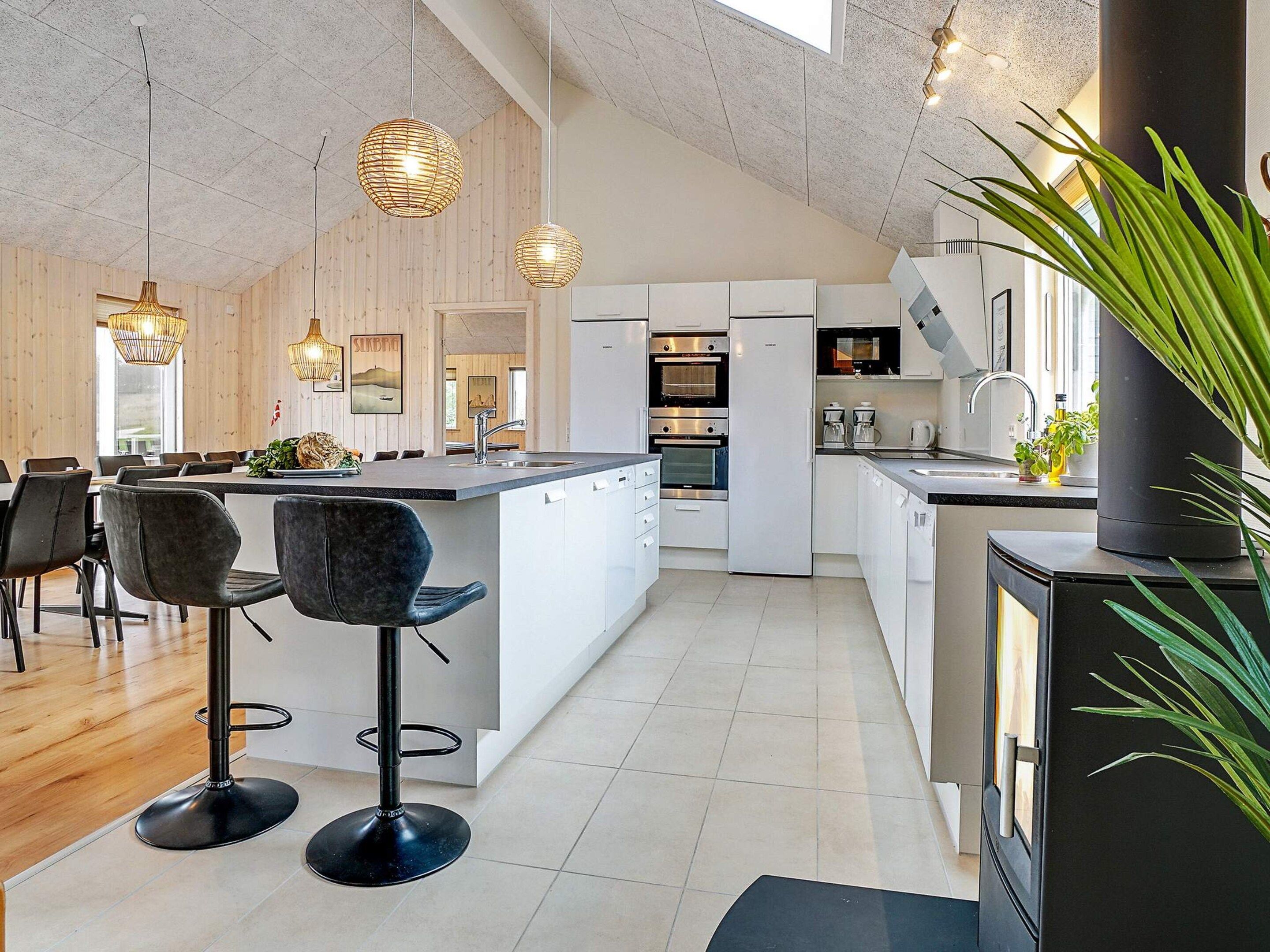 A modern kitchen with a central island, bar stools, and pendant lighting.