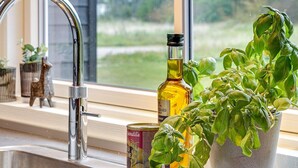 Une cuisine équipée d’un robinet en acier inoxydable, d’un pot de basilic, d’une boîte d’huile d’olive et d’une bouteille d’huile d’olive.