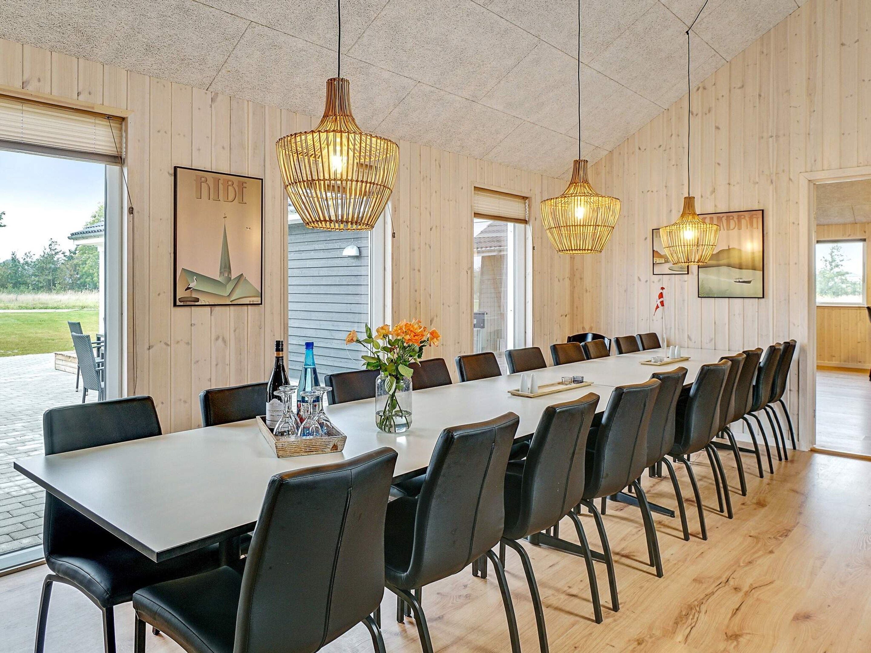 A conference room with a long table, chairs, and hanging lamps.