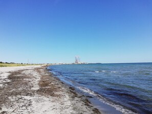 A beach with a clear sky, a sandy shore, and a distant structure. - Spacious Holiday Home in Grenå near Sea (Grenaa)