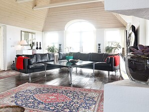 Un salon moderne avec un canapé en cuir noir, une table basse en verre et un tapis à motifs.