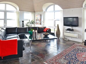 Ett modernt vardagsrum med en soffa i läder, ett soffbord i glas och en stor TV med platt skärm.