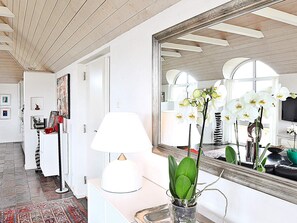 Ein Flur mit einer weißen Lampe, einem Spiegel und einem Blumentopf.