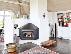 Un intérieur moderne avec une cheminée noire, des murs blancs et un grand tableau abstrait.