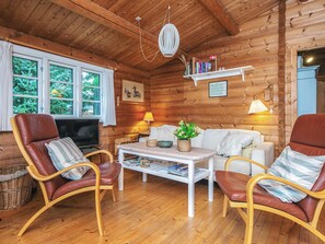 A cozy log cabin interior with a television, seating area, and bookshelves. - 6 Person Holiday Home in Oksbol (Oksbol)