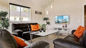 Ein modernes Wohnzimmer mit einer Ledersofa, einem Couchtisch und einem flachbildfernseher an der Wand.