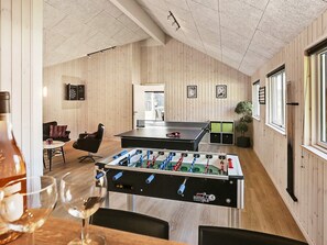 Een kamer met een tafelvoetbaltafel, een tafel met glazen en een stoel.