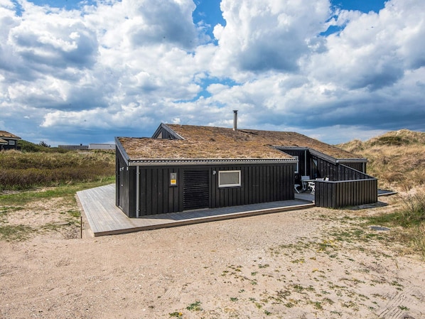 A modern building with a flat roof, a chimney, and a small deck area.