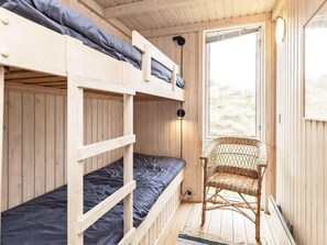 A wooden interior with bunk beds, a wicker chair, and a window. - 4 Star Holiday Home in Pandrup (Pandrup)