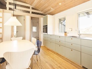 A modern kitchen with a wooden ceiling, a large window, and a built-in oven. - 4 Star Holiday Home in Pandrup (Pandrup)