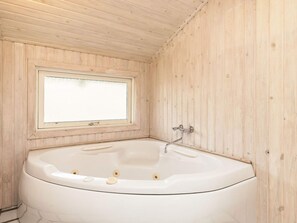 A room with a wooden interior, a large bathtub, and a window.
