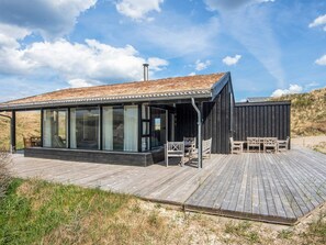 A modern building with large glass windows, a wooden deck, and a black exterior.