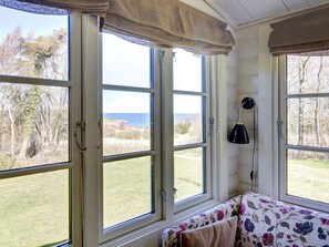A room with large windows, a bench, and a lamp. - 4 Person Holiday Home in Allinge (Allinge)