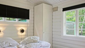 A room with two beds, white bedding, a red and white flag on the lower bed, and a window with blinds. - 4 Person Holiday Home in Allinge (Allinge)