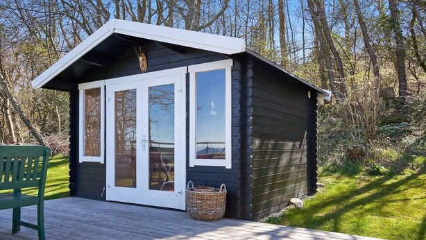 A cabin with a deck, a green chair, and a basket. - 4 Person Holiday Home in Allinge (Allinge)