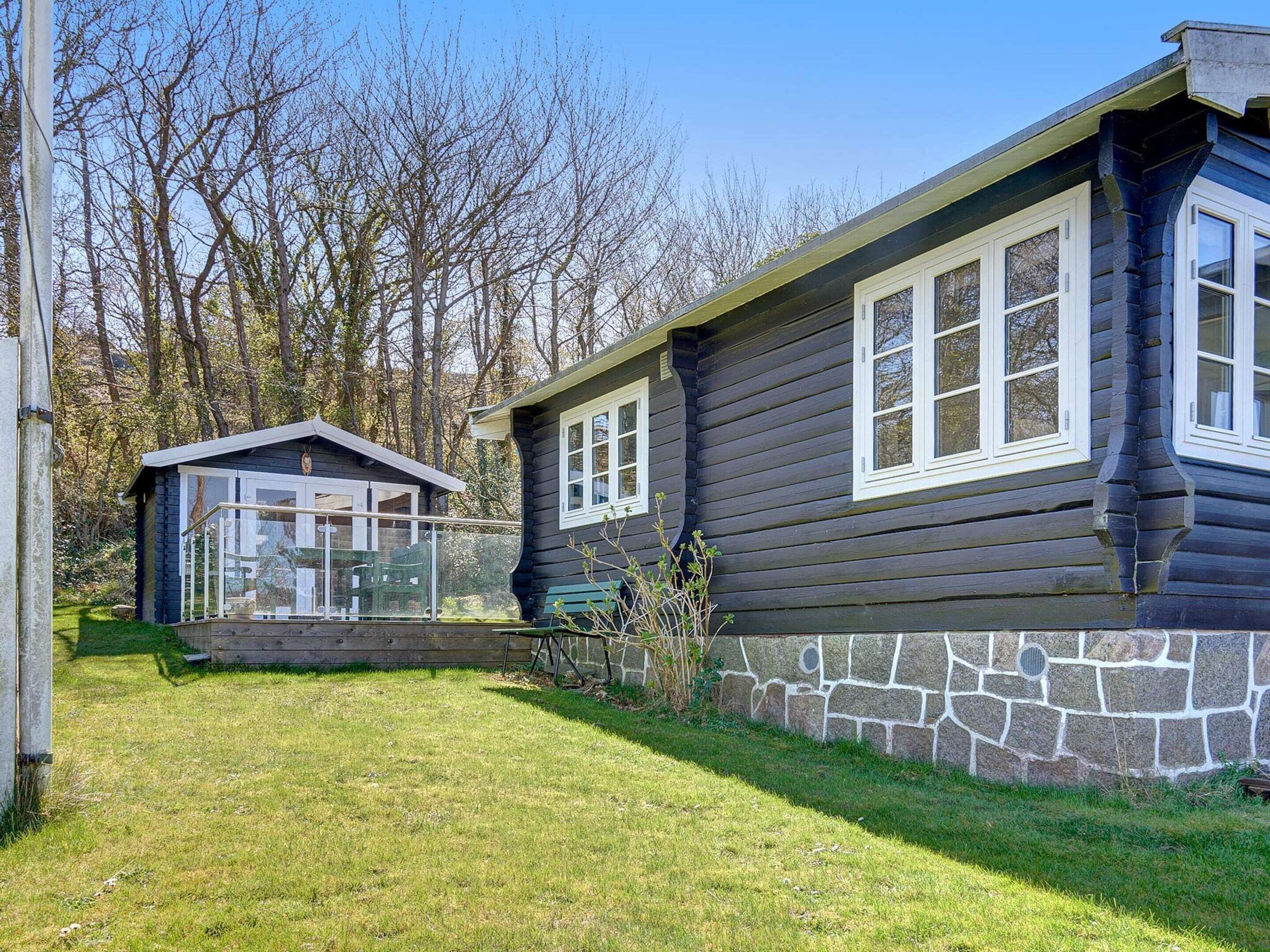 A log cabin with a stone foundation and a small attached structure.