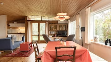 A cozy living room with a dining table, chairs, a sofa, and a television.
