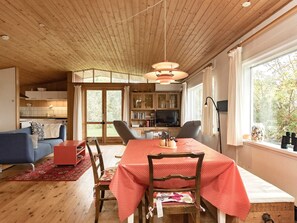 A cozy living room with a dining table, chairs, a sofa, and a television.