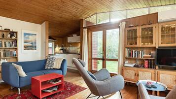 A spacious living area with a blue sofa, a red coffee table, and a grey rocking chair.