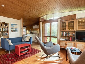 A spacious living area with a blue sofa, a red coffee table, and a grey rocking chair. - 4 Person Holiday Home in Martofte-by Traum (Martofte)