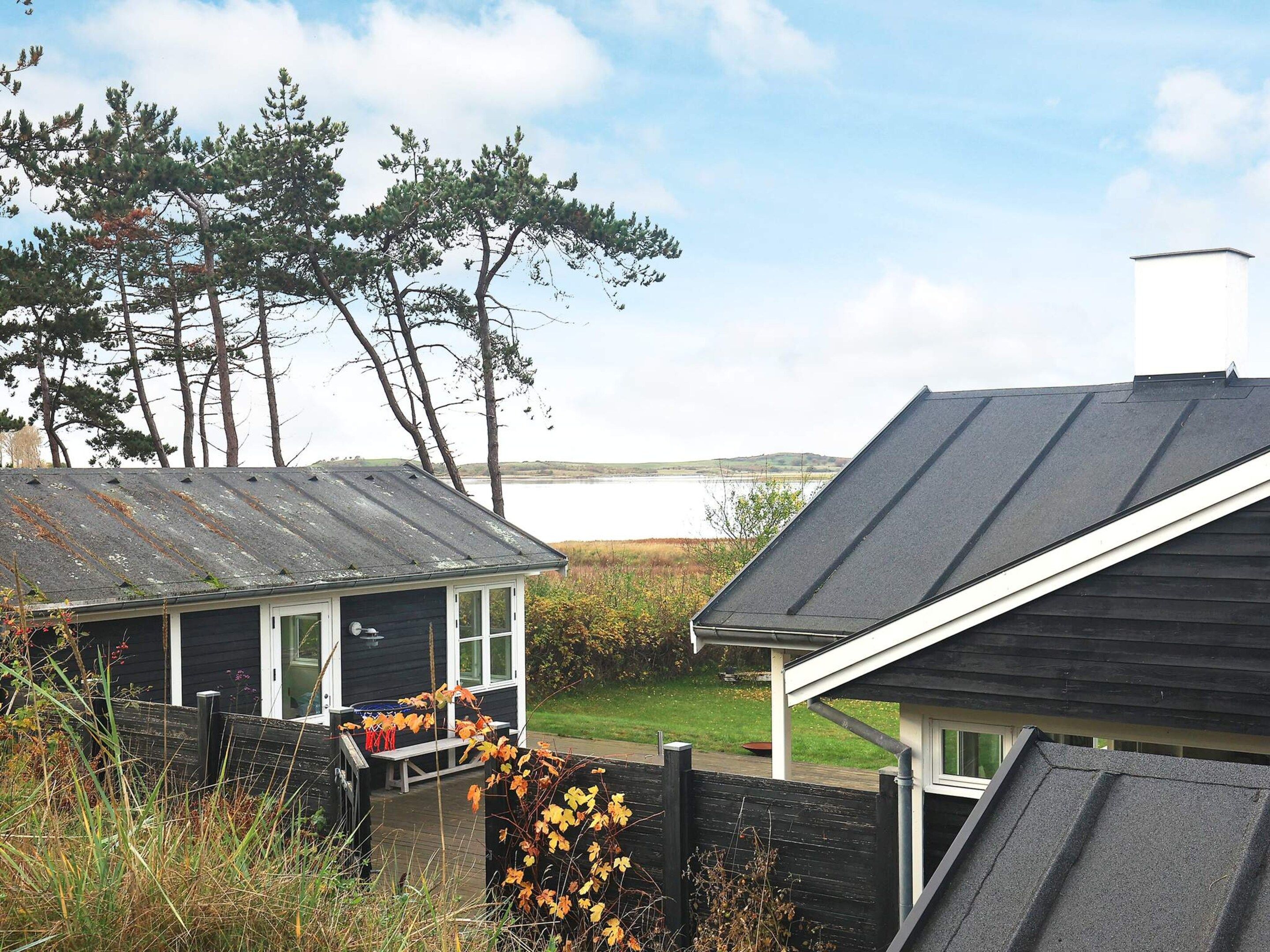 A coastal property with a small cabin and a larger building, both with metal roofs, overlooking a body of water.