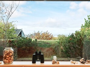 A window with binoculars, a jar of nuts, and a can on a ledge. - 4 Person Holiday Home in Martofte-by Traum (Martofte)