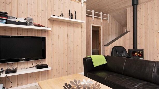 Uma sala de estar moderna com uma televisão de tela plana, um sofá de couro preto, uma mesa de centro de madeira e uma lareira a lenha preta.