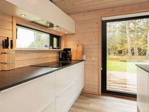 A modern kitchen with wooden cabinetry, a black countertop, and a large window. - 5 Star Holiday Home in Hals (Hals)