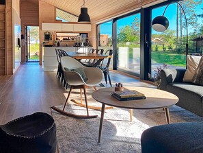 A modern interior with a dining area, a kitchen, and a living space with large windows.
