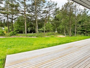 A wooden deck with a view of a grassy area and trees.