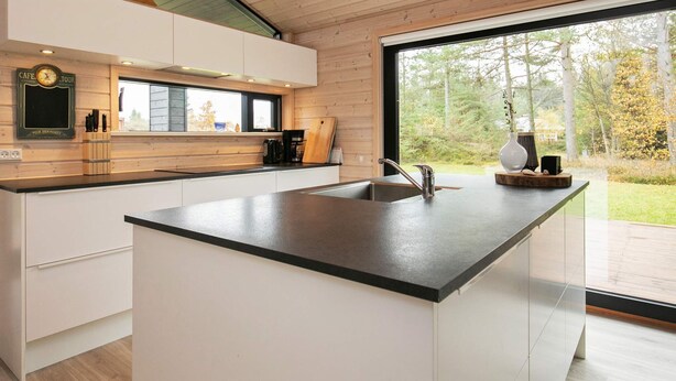 A modern kitchen with a large island, wooden cabinetry, and a view of the outdoors. - 5 Star Holiday Home in Hals (Hals)