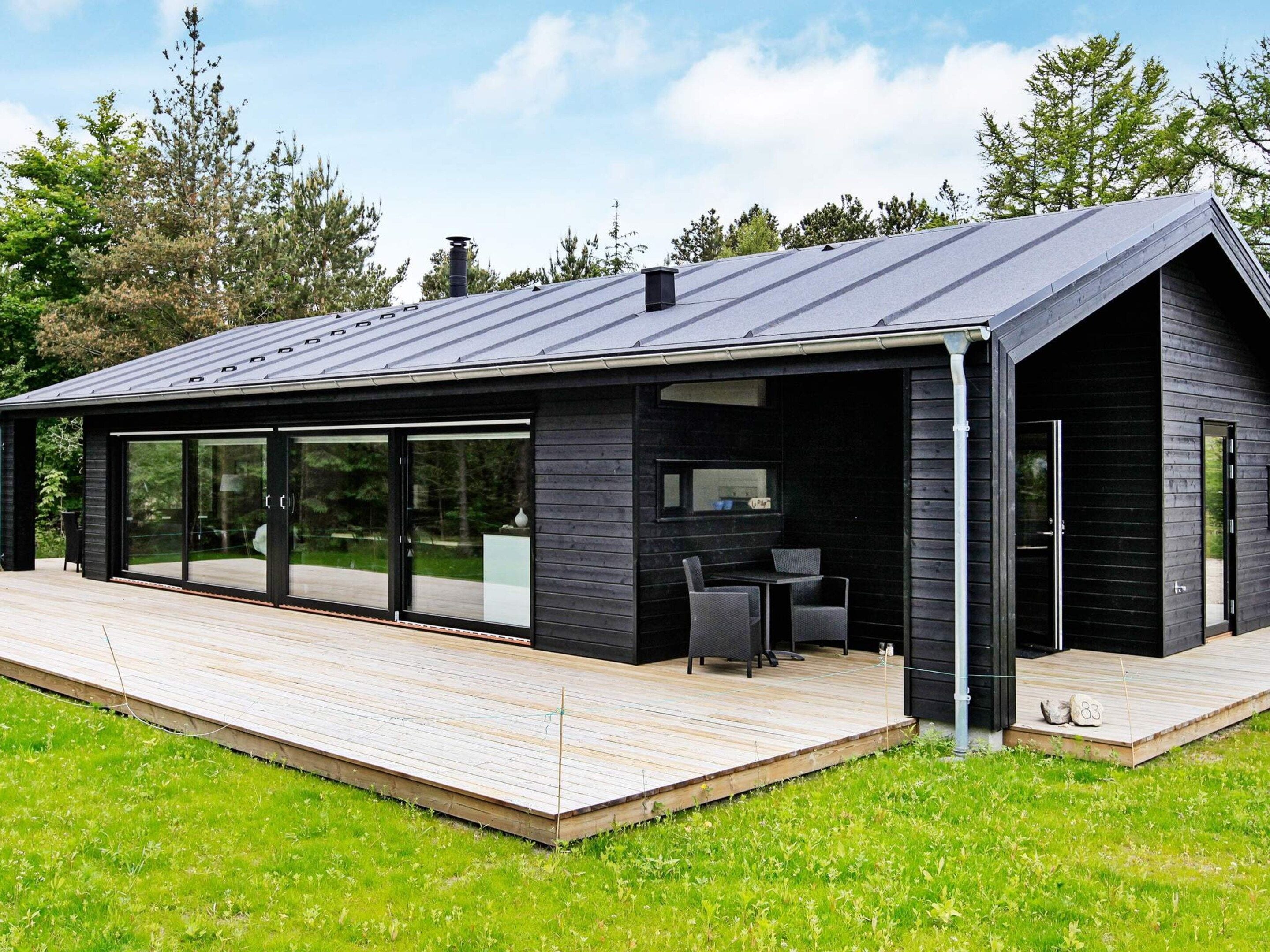 A modern house with a large deck, sliding glass doors, and a dark exterior.