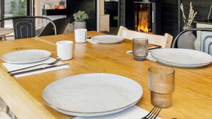 A dining table set with plates, cutlery, and glasses, with a fireplace in the background. - 5 Star Holiday Home in Hals (Hals)