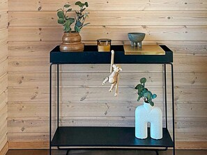 A wooden wall with a black metal shelf holding a vase, a bowl, and a hanging wooden figure. - 5 Star Holiday Home in Hals (Hals)