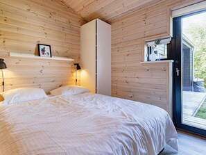 A bedroom with a bed, bedside lamps, a white wardrobe, and a sliding glass door leading to an outdoor area. - 5 Star Holiday Home in Hals (Hals)