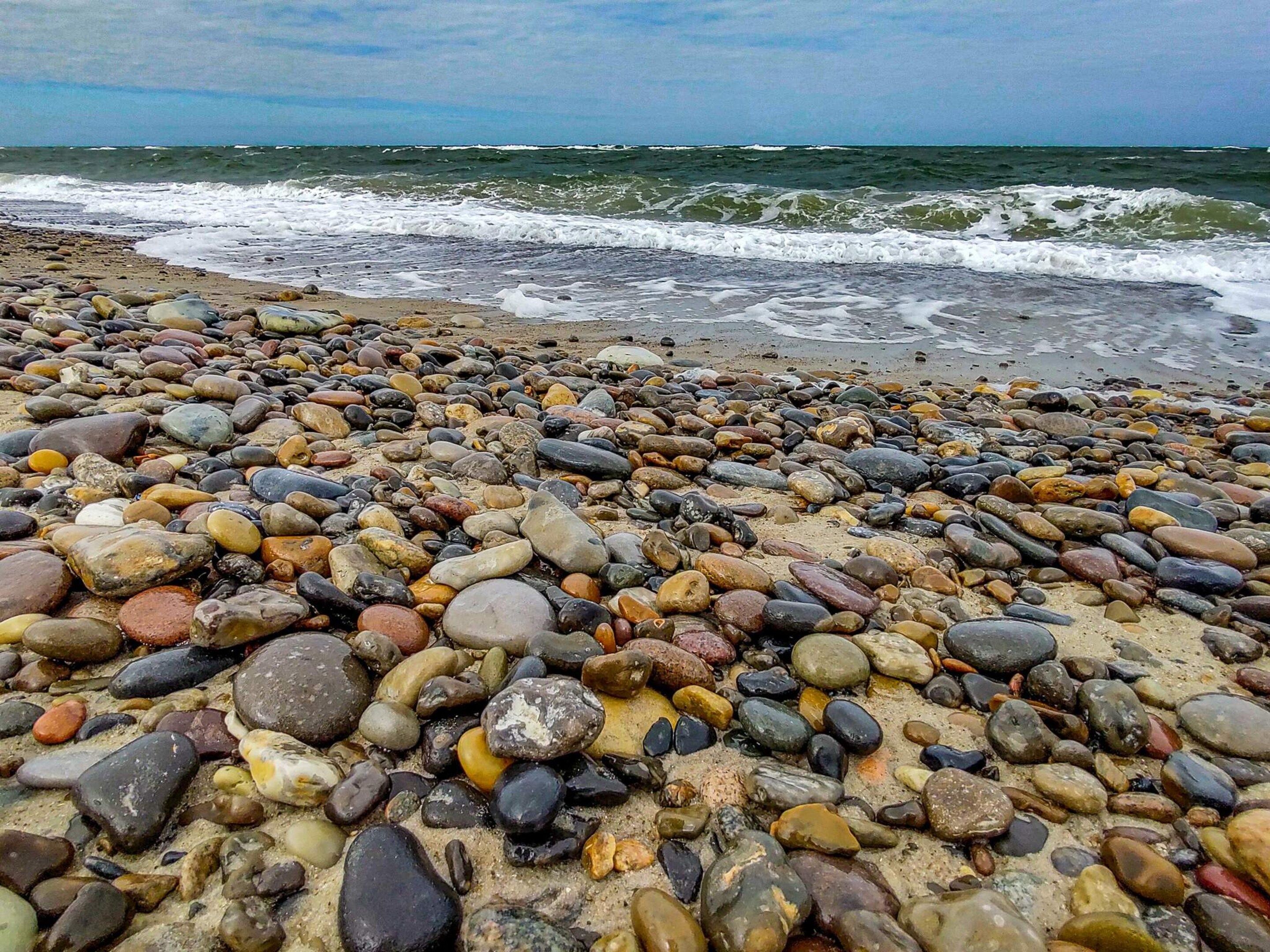 Une plage de galets avec des vagues en arrière-plan.