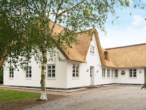 A white building with a thatched roof and multiple windows.