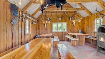 Interior rústico de una cabaña con paredes de madera, techo con astas de ciervo y chimenea.