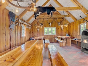 A rustic lodge interior with wooden walls, a ceiling with antlers, and a fireplace.