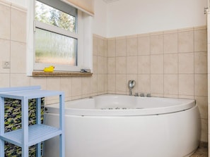 A bathroom with a large bathtub, a window with a view, and a shelf with a yellow rubber duck. - 5 Star Holiday Home in Hals (Hals)