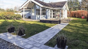 A modern two-story house with a covered porch, a landscaped front yard, and a swing set. - 5 Star Holiday Home in Hals (Hals)