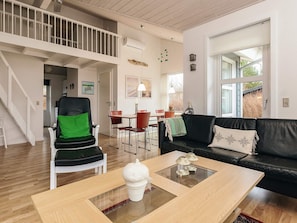 A modern living room with a staircase, a dining area, and a large window. - 5 Star Holiday Home in Hals (Hals)