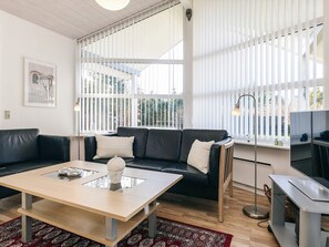 A modern living room with a black leather sofa, a wooden coffee table, and a television on a stand. - 5 Star Holiday Home in Hals (Hals)