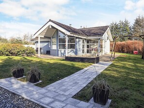 A modern house with a covered porch, a well-maintained lawn, and a swing set.