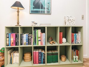 A bookshelf with various books, a lamp, and a small house model. - 5 Star Holiday Home in Hals (Hals)