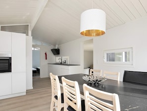 A modern kitchen with white cabinetry, a black countertop, and a wooden dining table with four chairs.