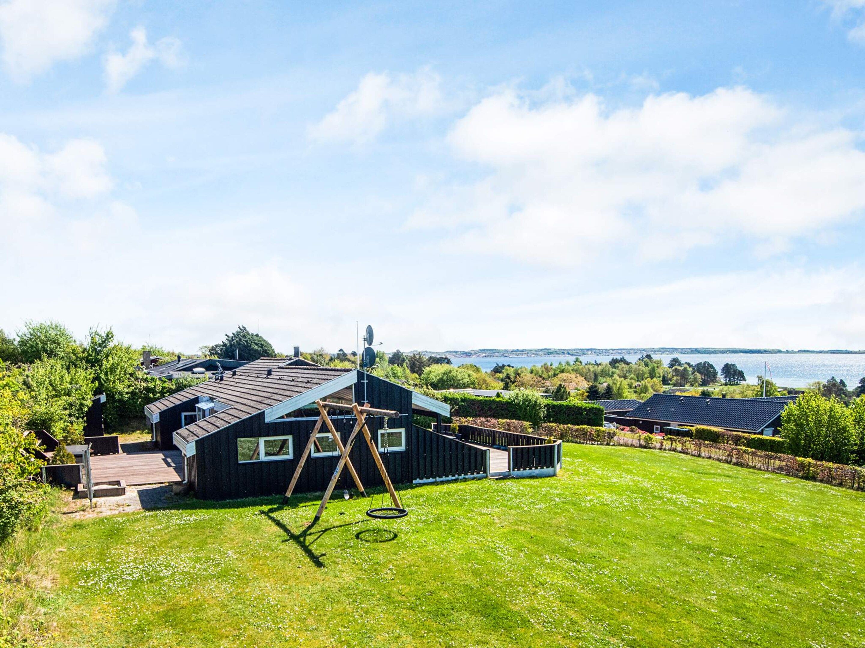 A residential property with a large lawn, a wooden deck, and a view of a body of water.